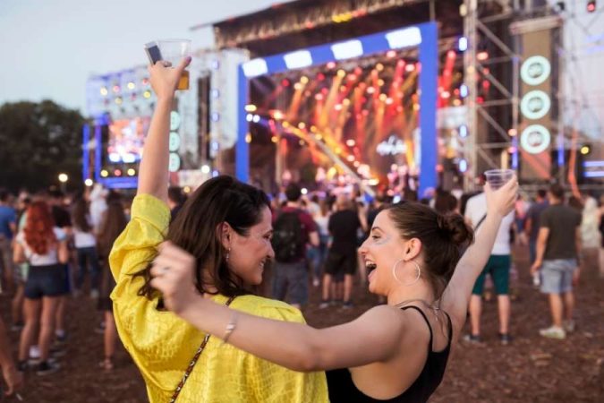 Deux femmes dansent et lèvent les bras au milieu d’un grand concert en plein air lors de Festivals de musique en France.