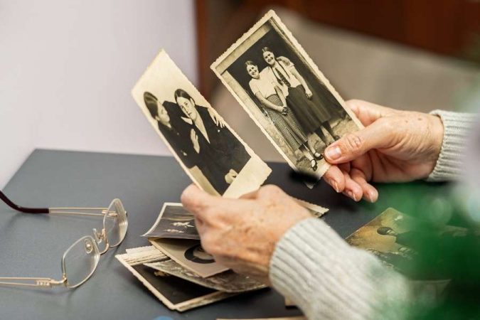 Une personne âgée regarde des clichés anciens, symbolisant des photos de famille naturelles et pleines de nostalgie.