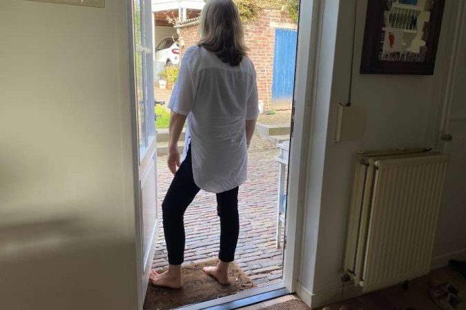 Une personne se tenant dans l'encadrement d'une porte ouvrant sur l'extérieur, équipée de baguettes de seuil de porte.